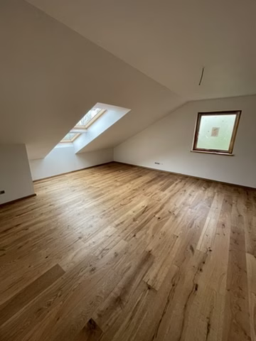Home 25 Heller Dachgeschossraum mit lebhaft gemasertem Bodenbelag in Holzoptik