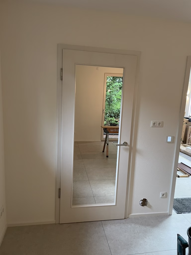 Home 30 Weiße Innentür mit großem klarem Glasausschnitt und Edelstahlgriff in einem gefliesten Raum