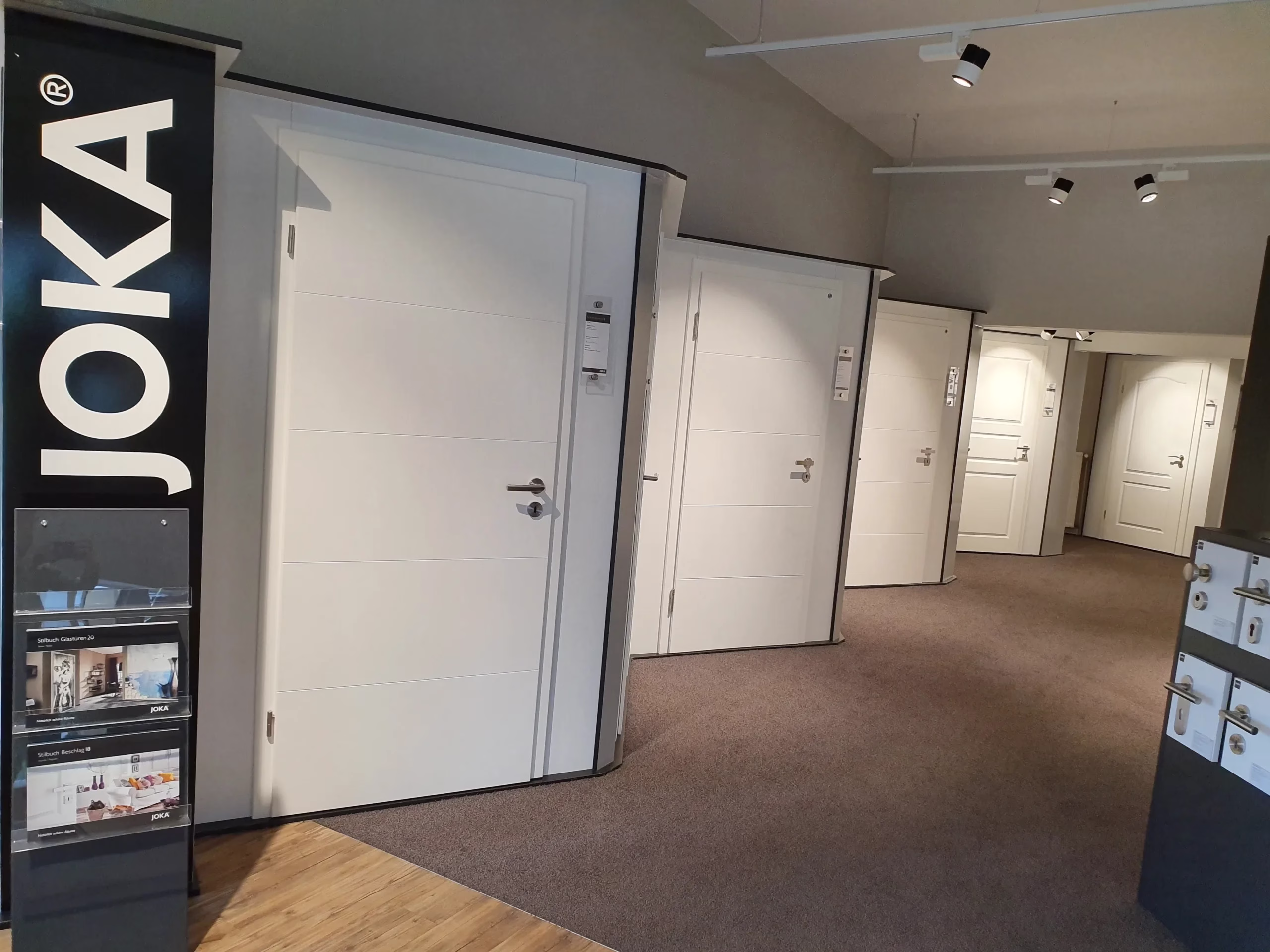 Mehrere weiße Türen in der JOKA-Ausstellung mit sichtbarem JOKA-Schriftzug