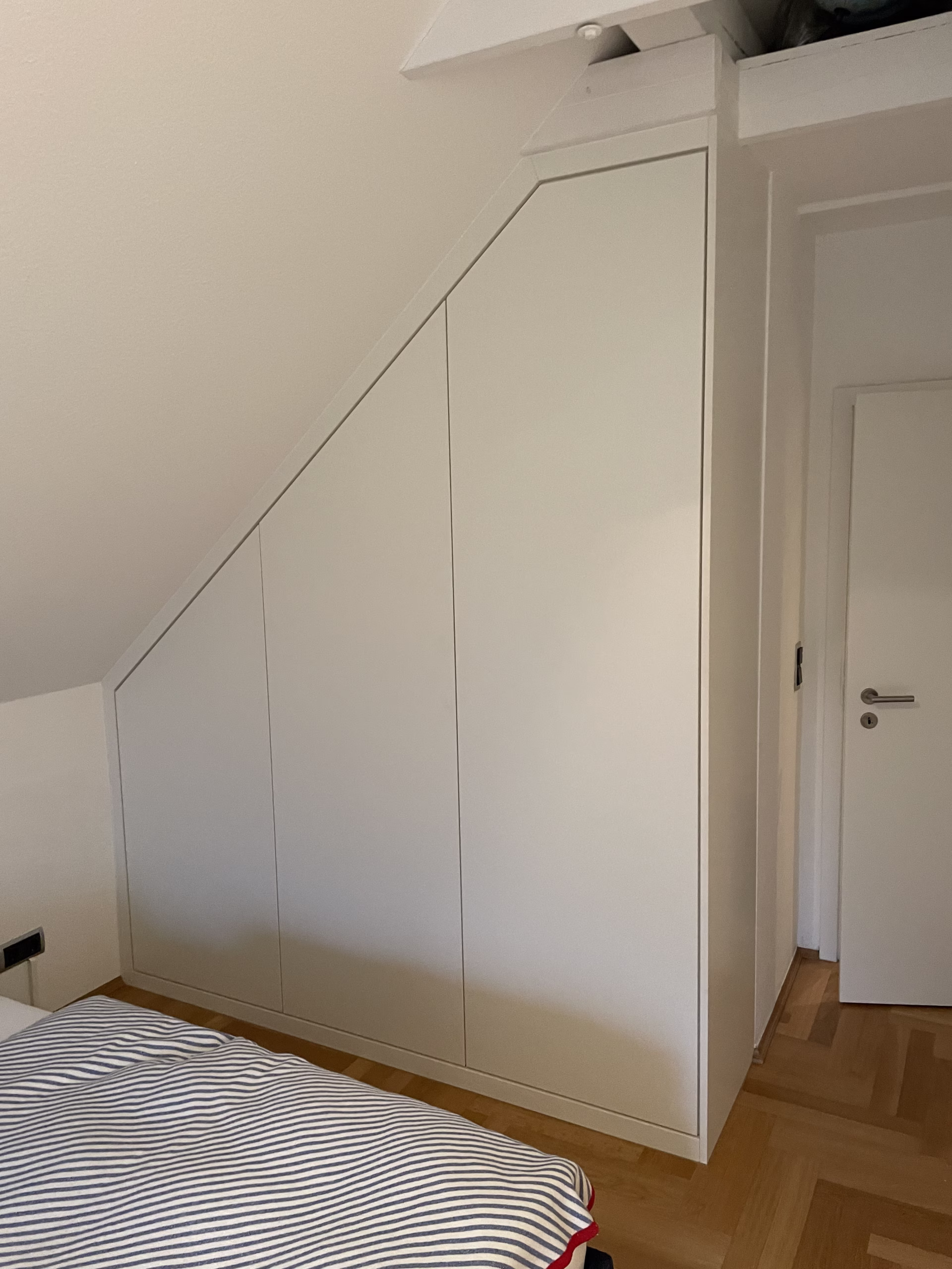 Geschlossener weißer Einbauschrank unter einer Dachschräge