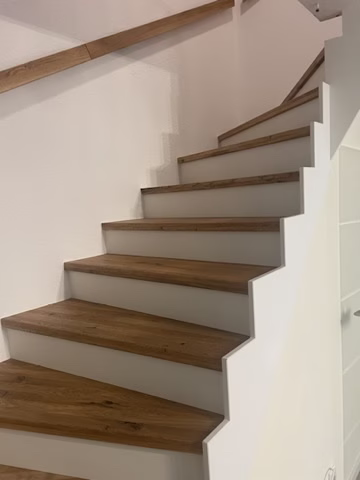 Betontreppe mit Holzstufen verkleiden: Was bei der Planung zählt 1 Treppenlauf mit weißen Setzstufen und wandseitigem Handlauf