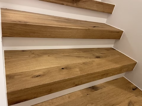 Detail keilförmiger holzfarbener Trittstufen und weißer Setzstufen