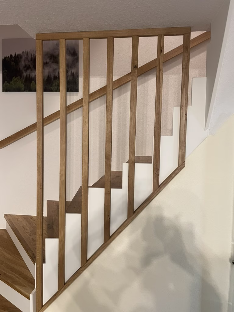 Home 31 Treppengeländer mit senkrechten Holzstäben und passendem Handlauf neben einer Treppe mit weißen Setzstufen